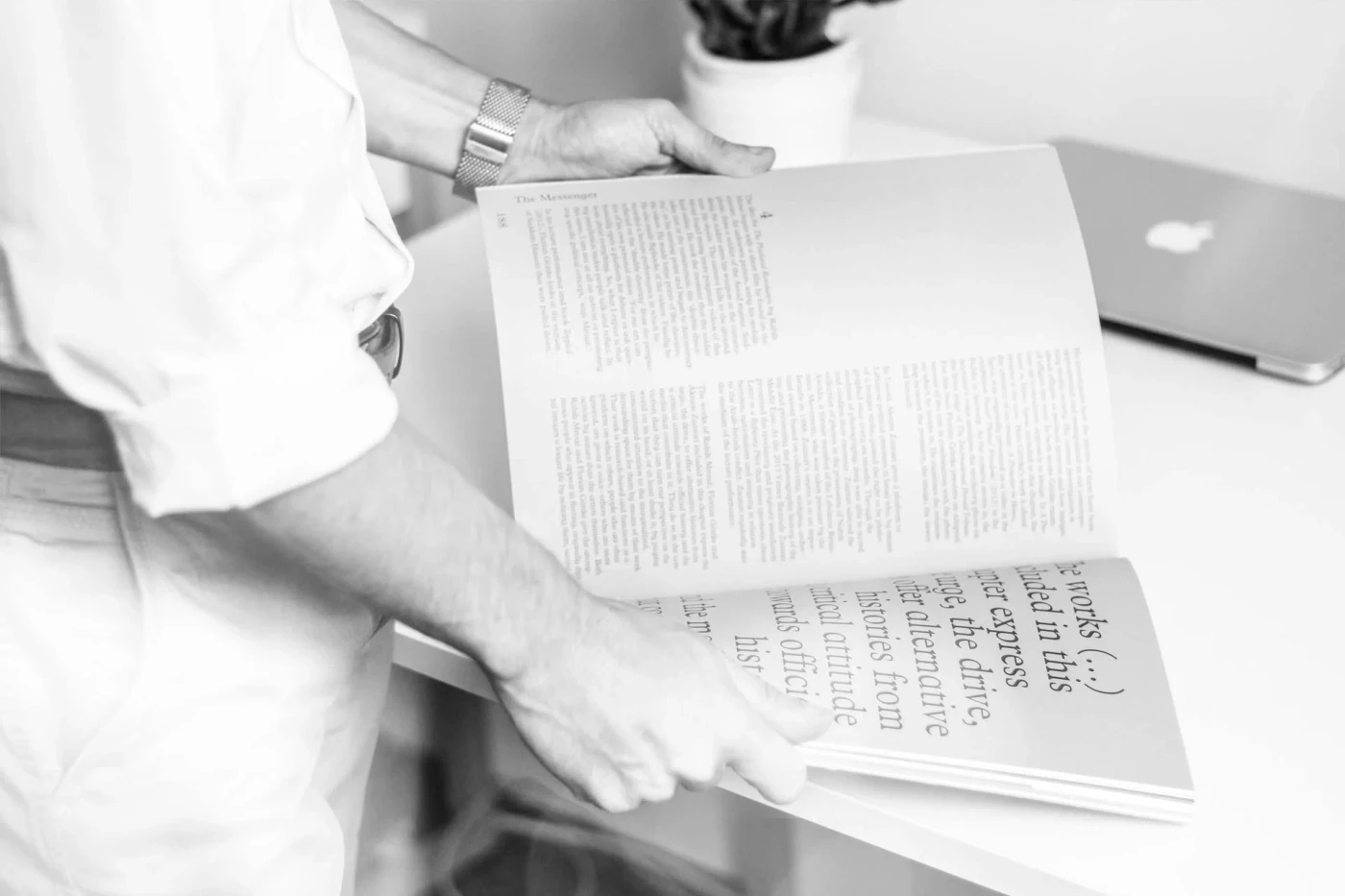 Schwarz-weißes Foto einer Person beim Lesen eines geöffneten Buches.